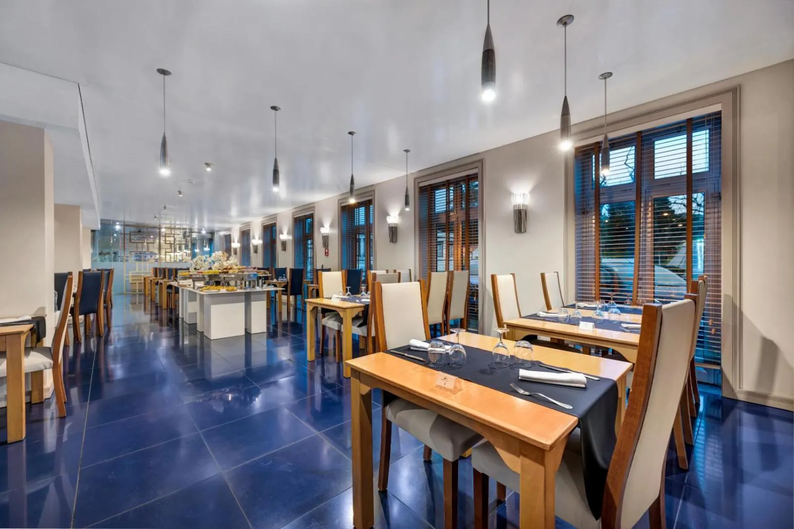 Une salle lumineuse avec des tables dressées pour un repas.