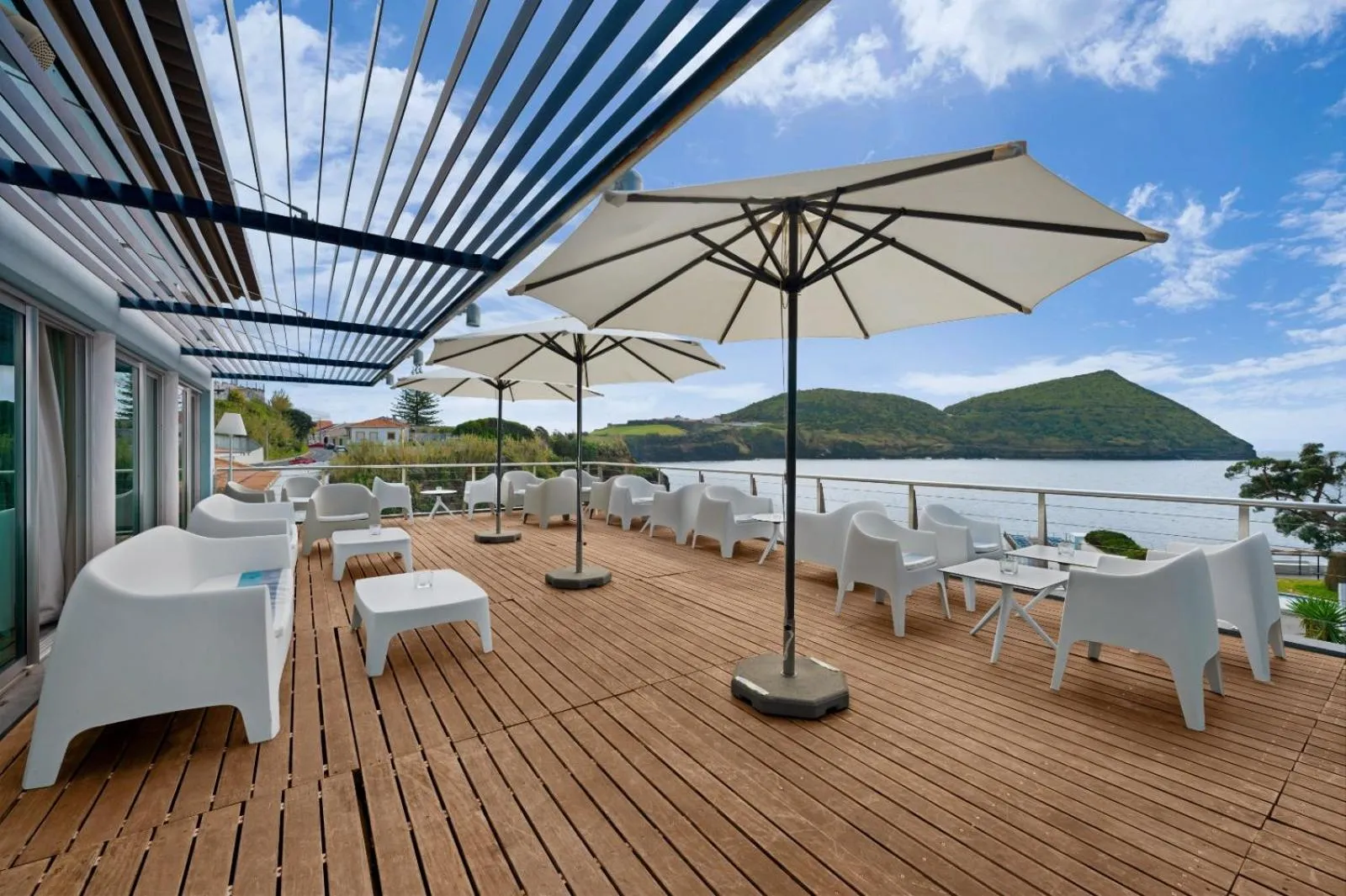 Terrasse en bois avec mobilier blanc et vue sur la mer.
