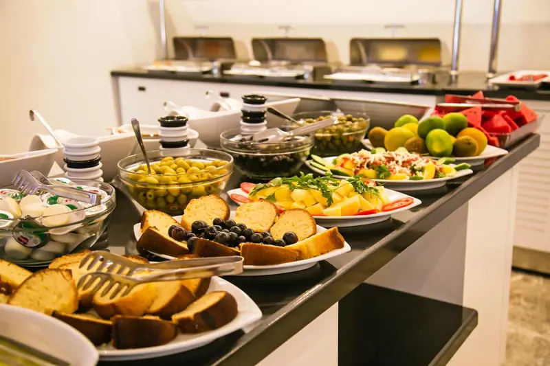 Un buffet propose une variété de fruits, de viennoiseries et de salades.