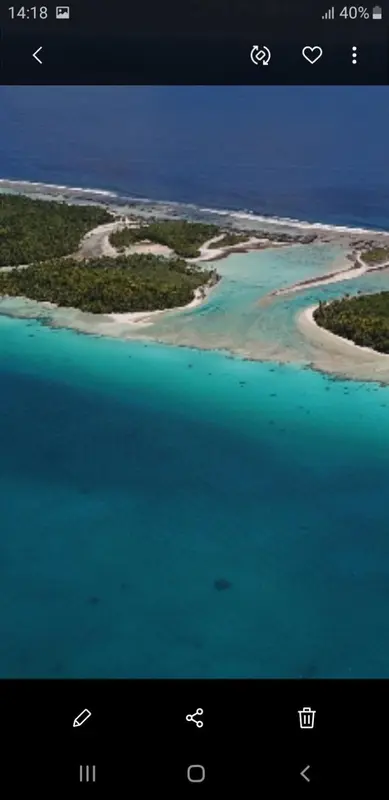 Vue aérienne d'une île tropicale bordée d'eaux turquoise et de plages de sable blanc.