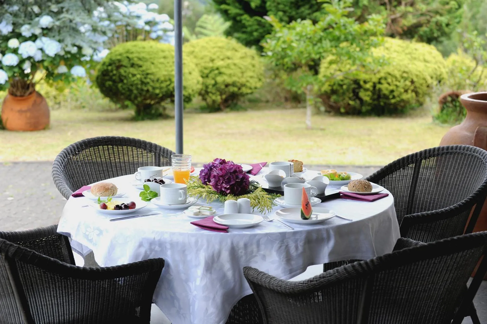 Une table ronde est dressée pour le petit-déjeuner sur une terrasse ombragée.