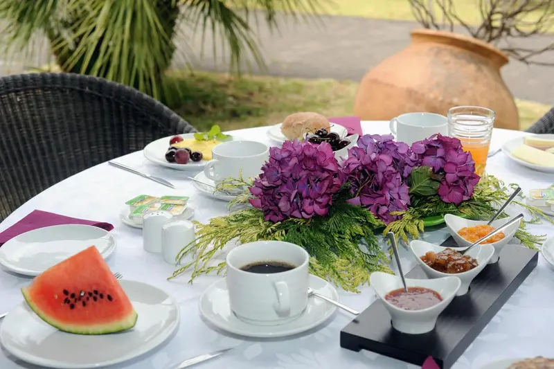 Une table ronde est dressée pour le petit-déjeuner avec des fruits, des viennoiseries et des boissons.