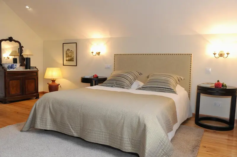 Une chambre lumineuse avec un grand lit et des meubles en bois.