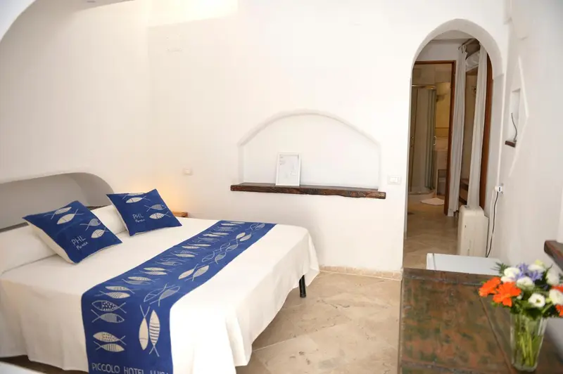 Une chambre lumineuse avec un lit recouvert d'une courtepointe marine et de coussins décoratifs.