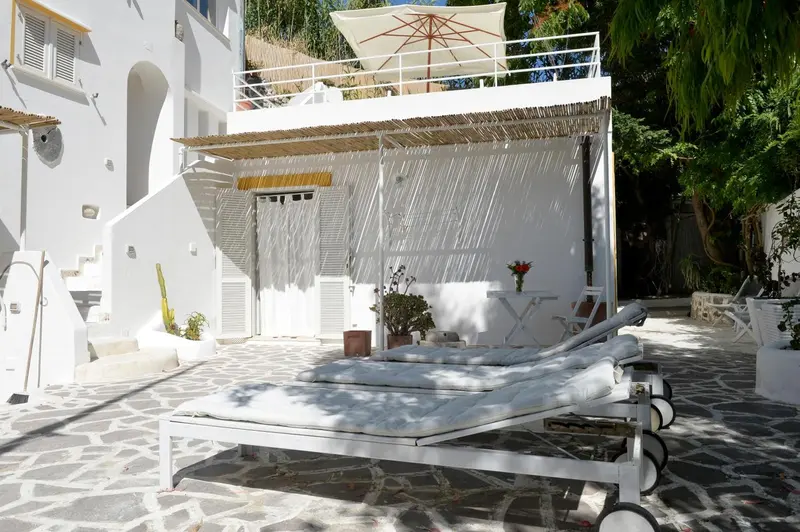 Terrasse ombragée avec chaises longues et végétation luxuriante.