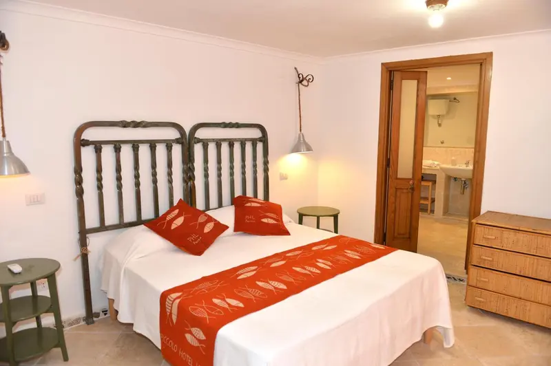 Une chambre lumineuse avec un lit recouvert d'une courtepointe décorative et un accès à une salle de bain.