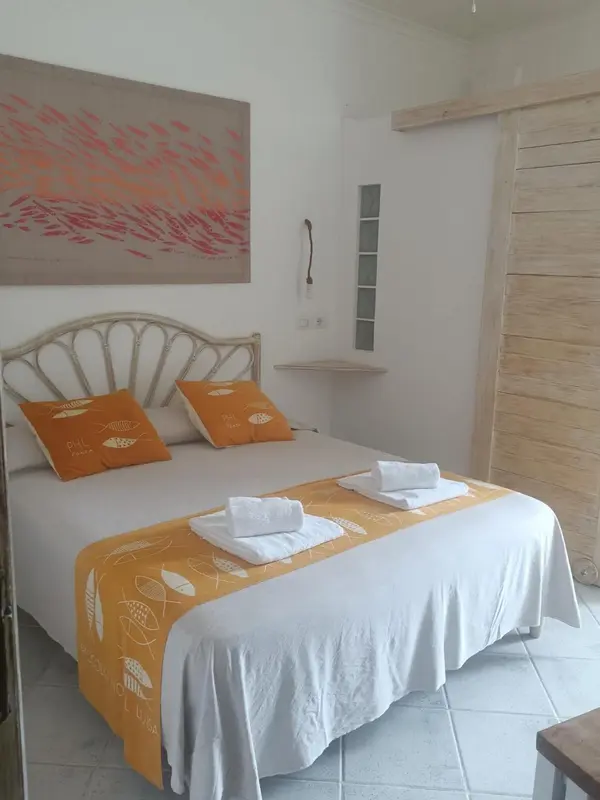Une chambre lumineuse avec un grand lit décoré de coussins et d'une courtepointe.