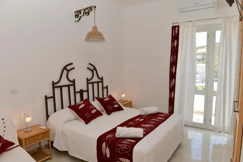 Une chambre lumineuse avec un lit recouvert d'une courtepointe décorative et des oreillers.