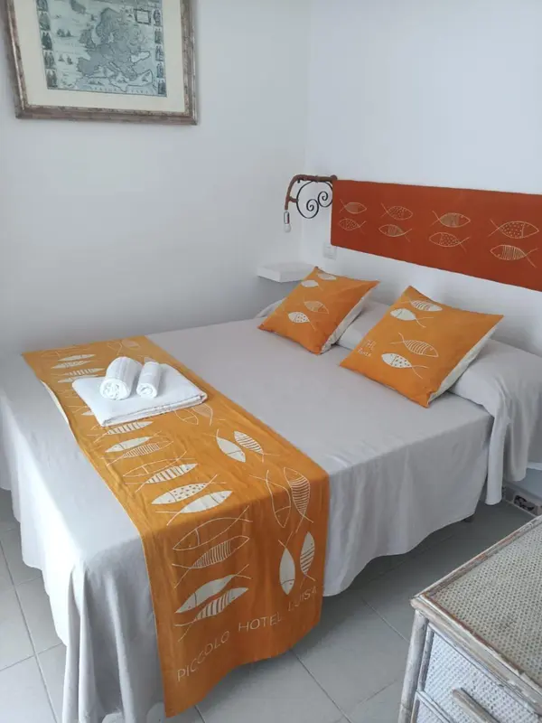 Une chambre lumineuse avec un lit recouvert d'une courtepointe et de coussins à motifs de poissons.