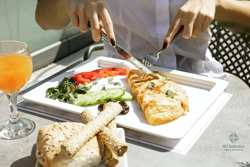 Une assiette de poisson grillé est présentée avec une salade et un verre de jus d'orange.