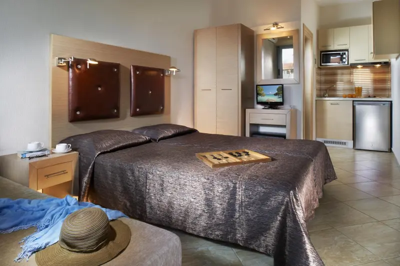 Une chambre avec un grand lit et un coin cuisine.
