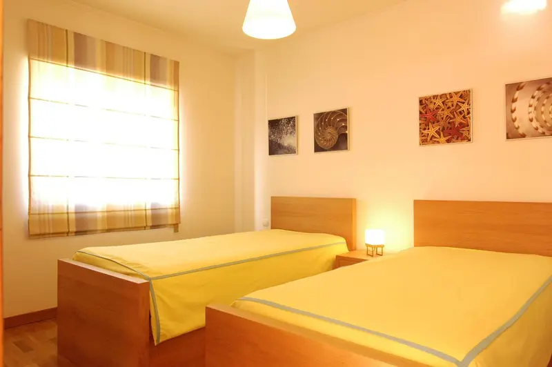 Une chambre lumineuse avec deux lits simples et des tableaux décoratifs.