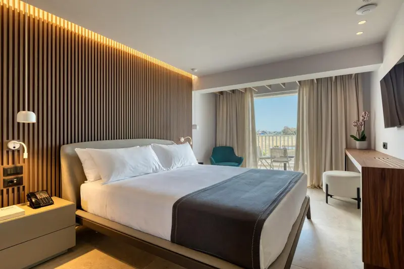 Une chambre lumineuse avec un grand lit et un accès à une terrasse.