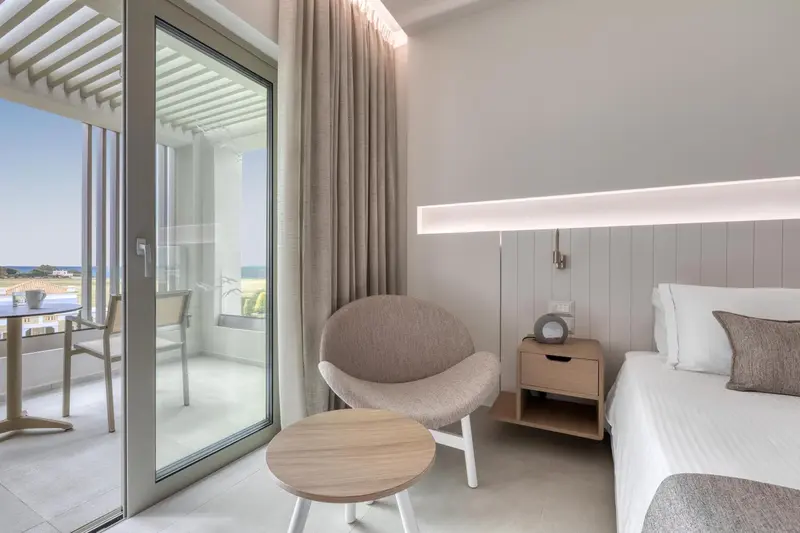 Une chambre lumineuse avec un coin salon et un balcon donnant sur la mer.