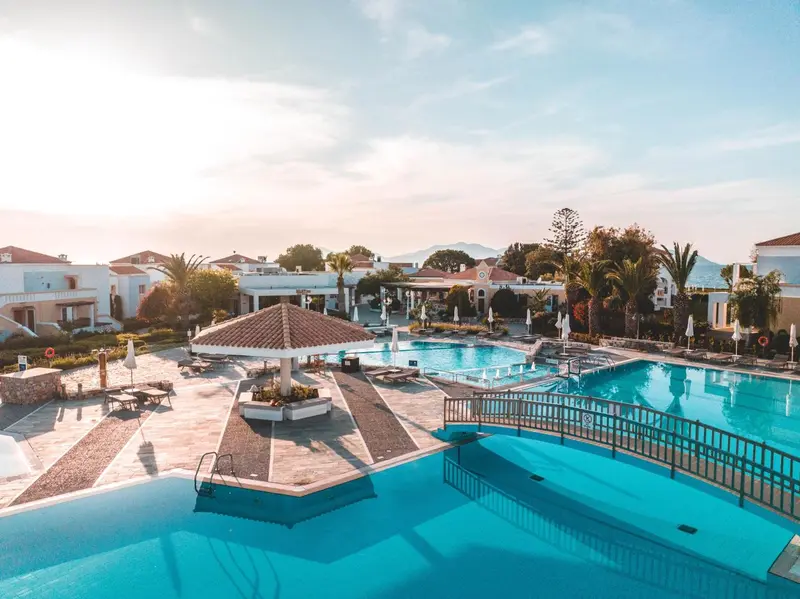 Vue aérienne d'un complexe hôtelier avec plusieurs piscines et des parasols.