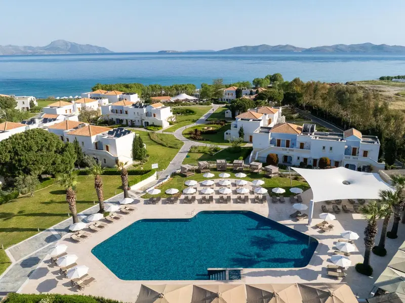Vue aérienne d'un complexe hôtelier blanc avec piscine et végétation luxuriante.