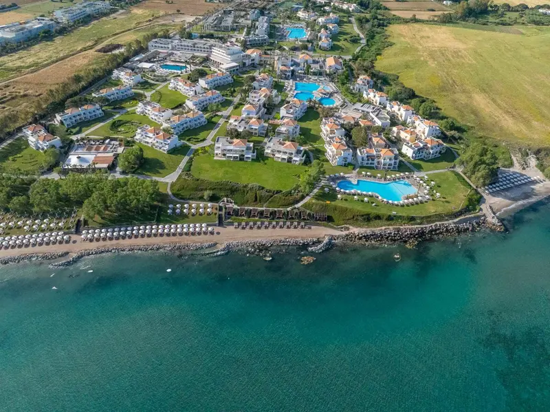 Vue aérienne d'un complexe hôtelier blanc avec des piscines et une plage.