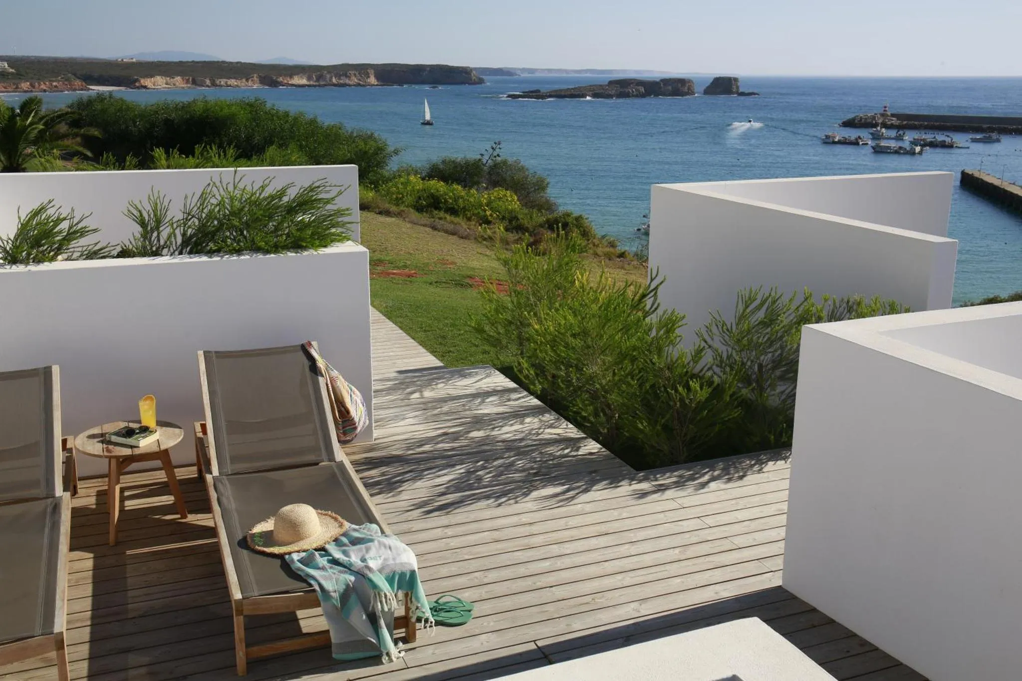 Terrasse en bois avec transats et vue sur la mer.