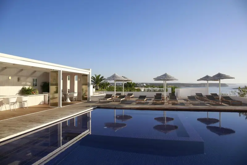 Terrasse avec transats et piscine au bord de la mer.