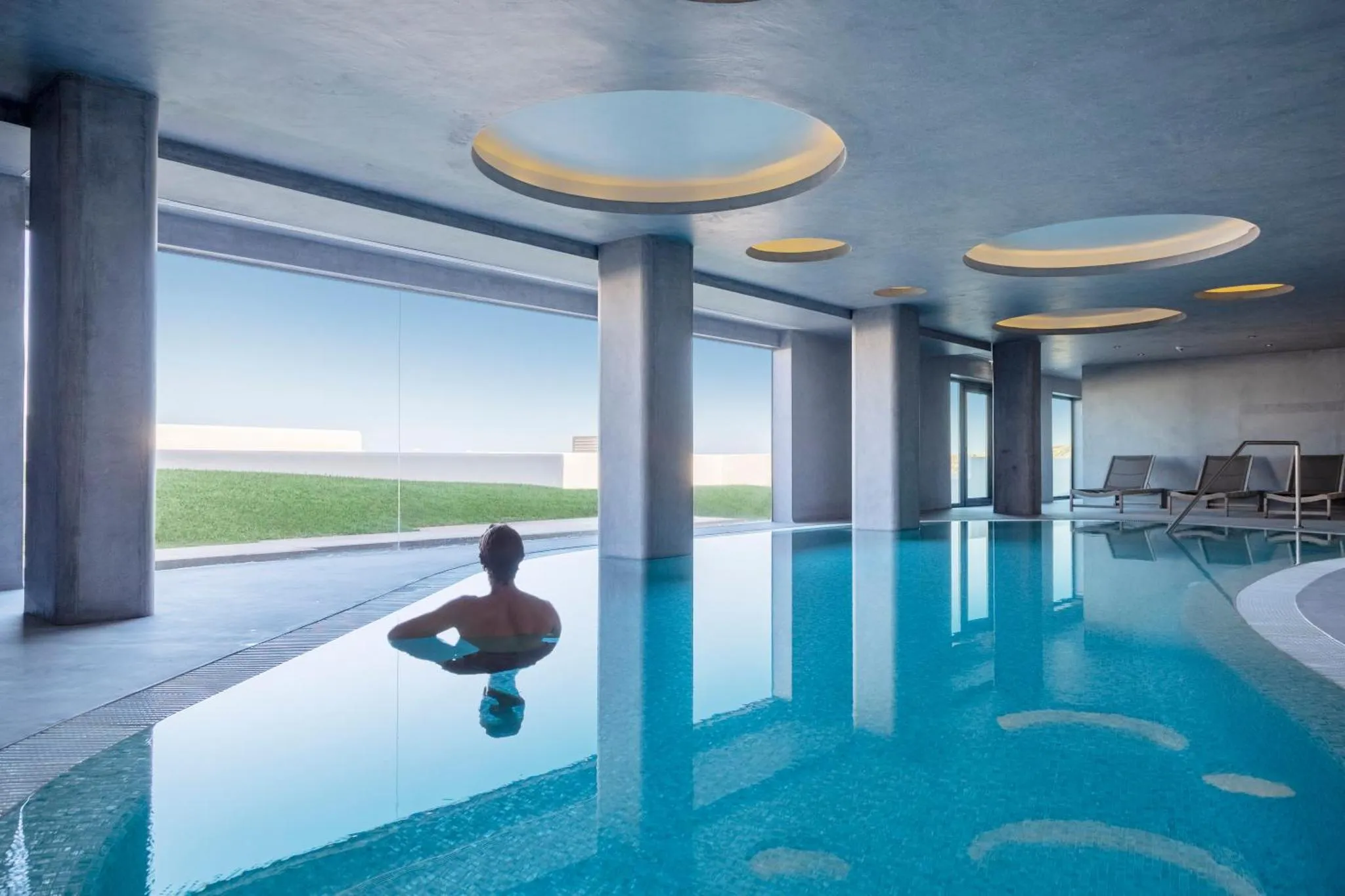 Une personne se détend dans une piscine intérieure lumineuse.