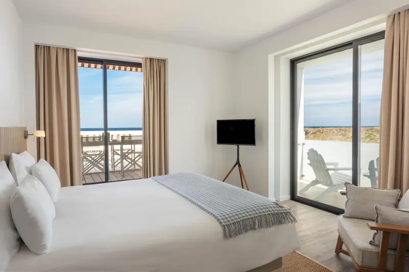 Une chambre lumineuse avec un lit fait et une vue sur la mer.