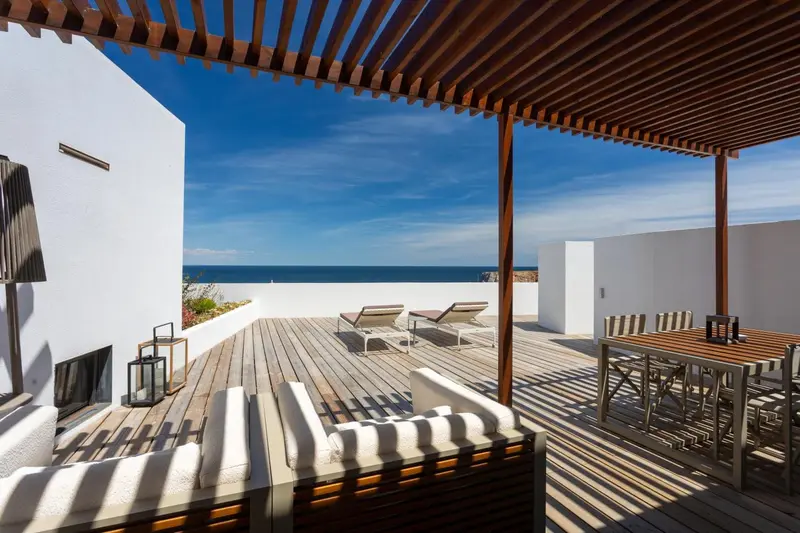 Terrasse en bois avec mobilier de détente et vue sur la mer.