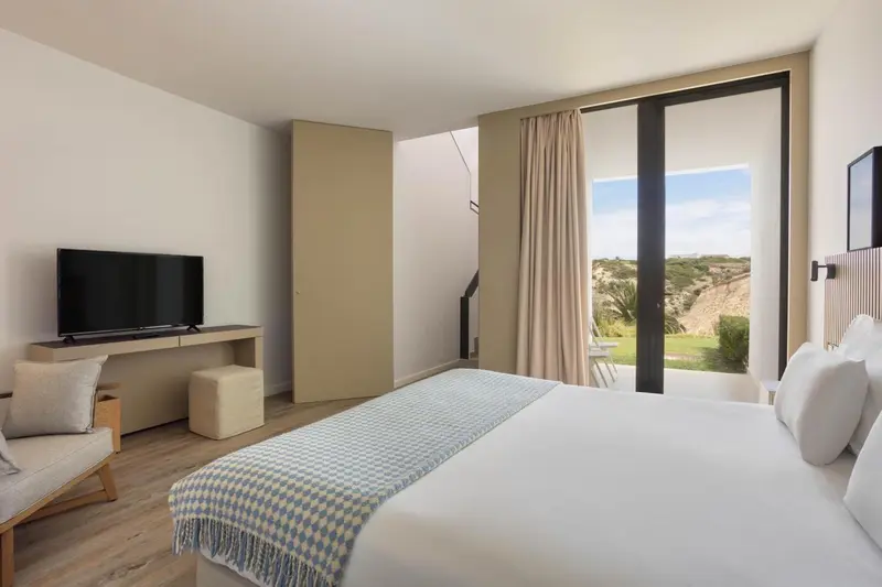 Une chambre lumineuse avec un grand lit et un accès à une terrasse.