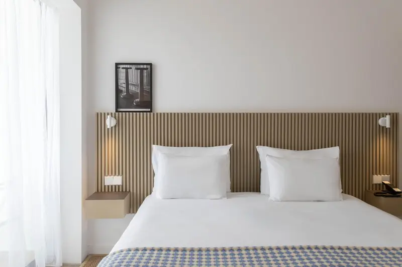 Une chambre lumineuse avec un grand lit et une tête de lit décorative.