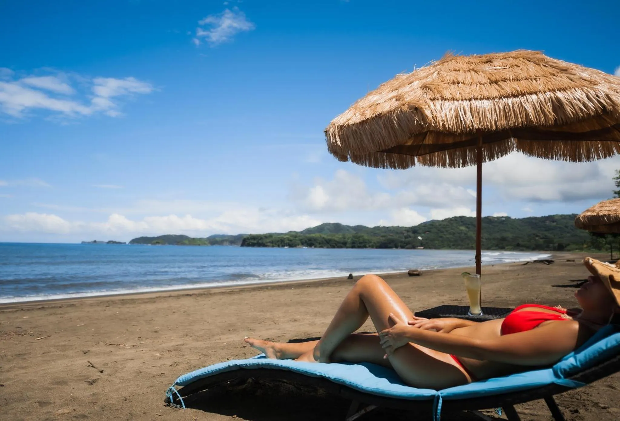 Une personne se relaxe sur une chaise longue sur une plage de sable fin.