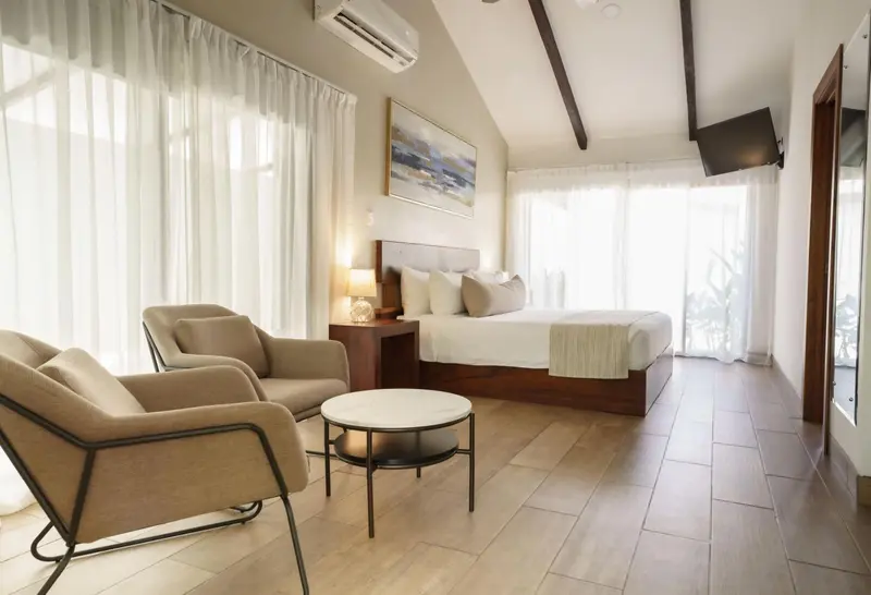Une chambre lumineuse avec un coin salon et un lit double.