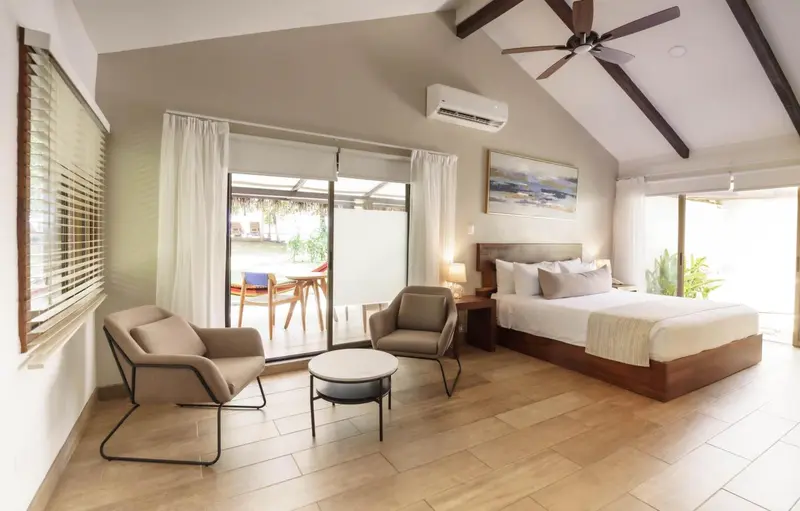 Espace de vie lumineux avec un lit et des fauteuils confortables.