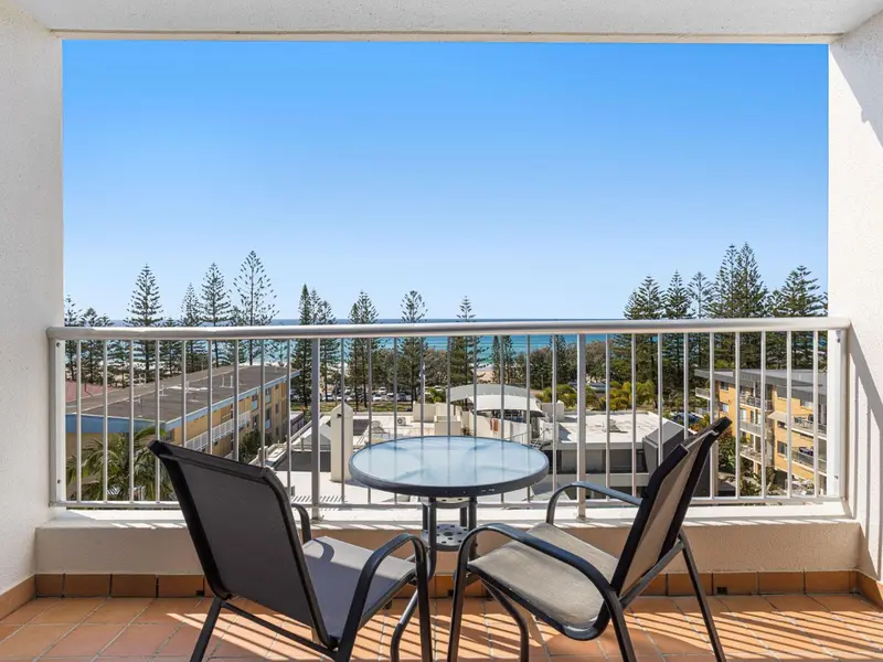 Vue sur la mer depuis un balcon aménagé avec des chaises et une table.
