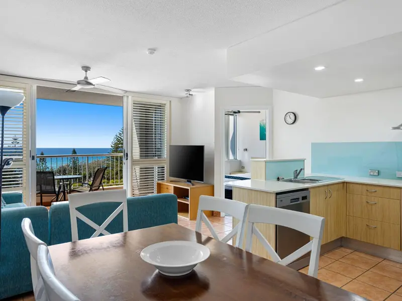 Interieur lumineux avec espace repas et cuisine ouverte donnant sur une terrasse.