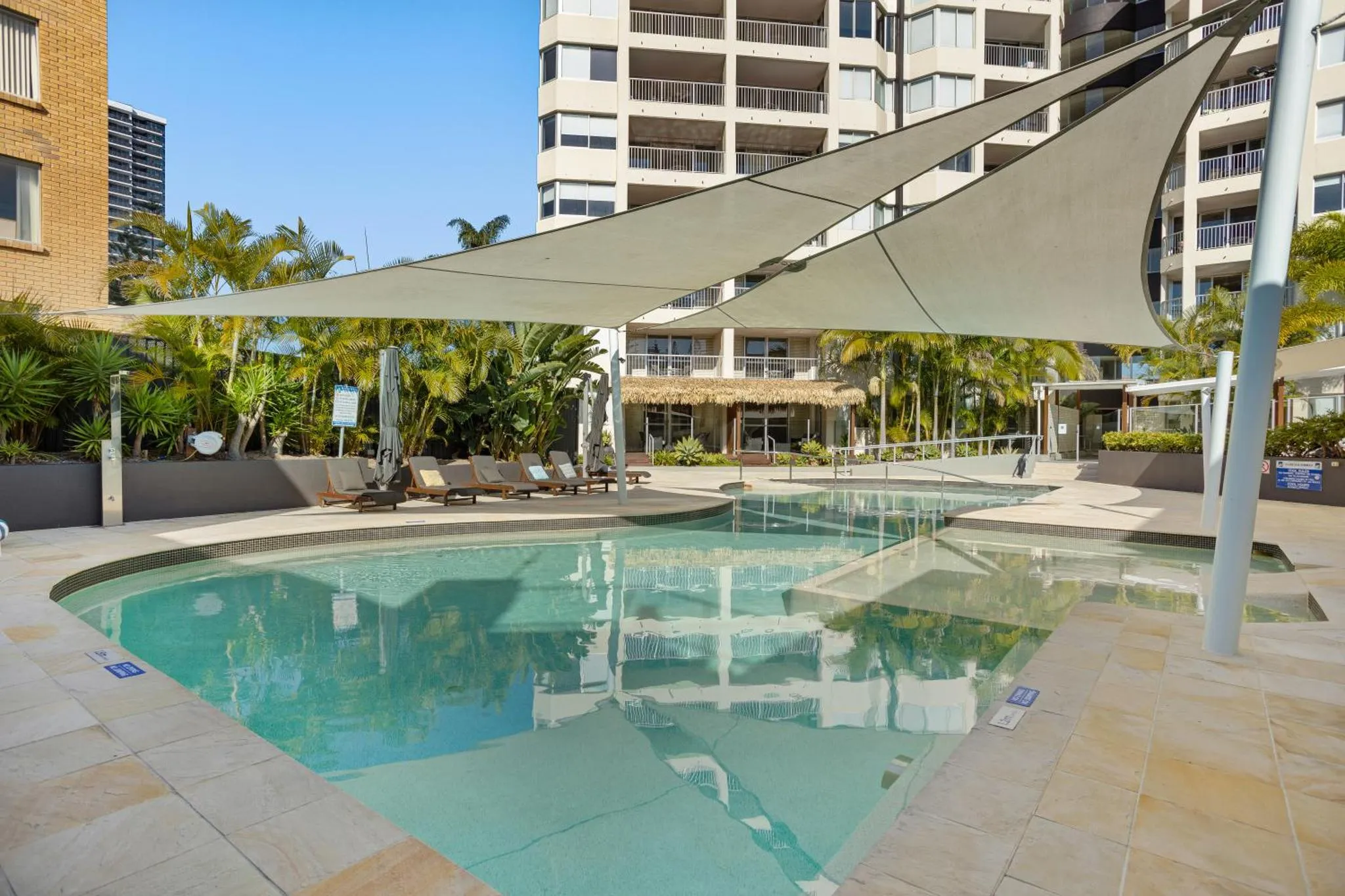 Piscine rectangulaire bordée d'une terrasse ensoleillée avec des transats.