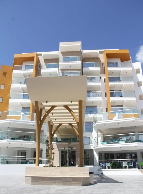 Façade d'un bâtiment moderne avec des balcons et une entrée ombragée.