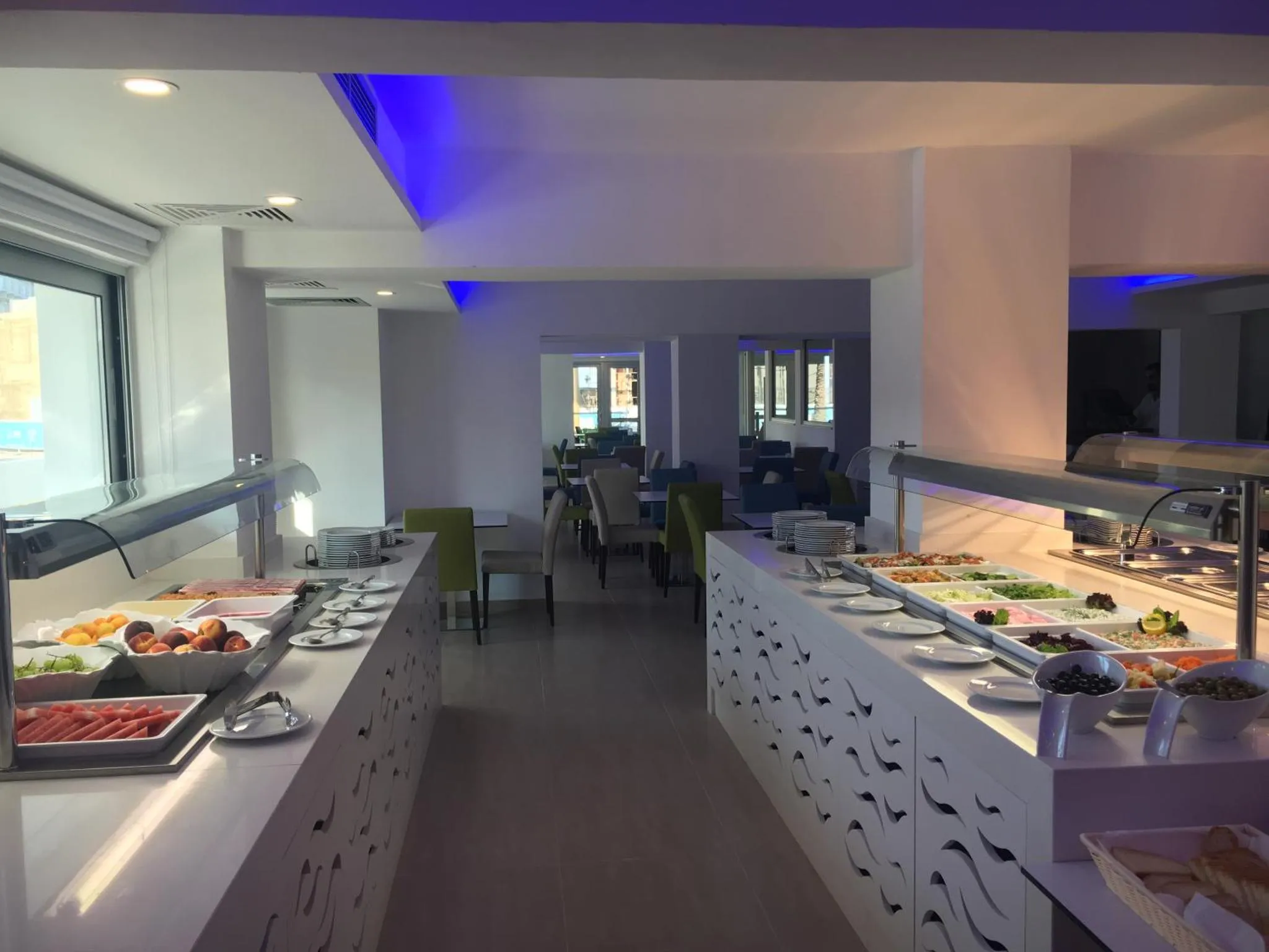 Un buffet propose une variété de plats frais et colorés dans une salle lumineuse.