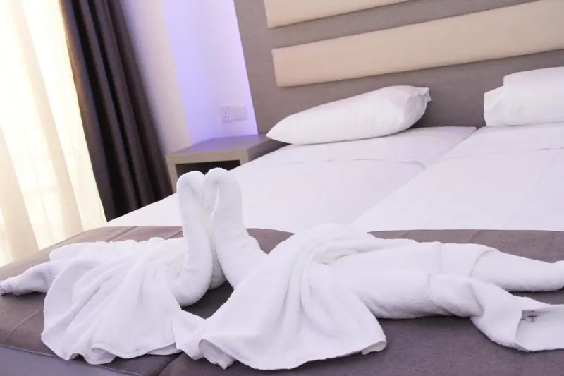 Un lit est soigneusement fait avec des serviettes en forme de cygnes sur le couvre-lit.