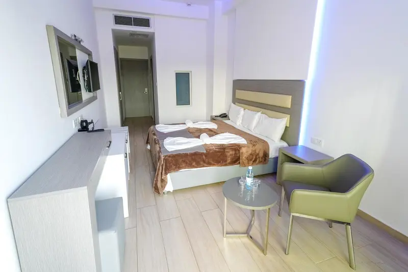 Une chambre lumineuse avec un lit double et un coin salon.