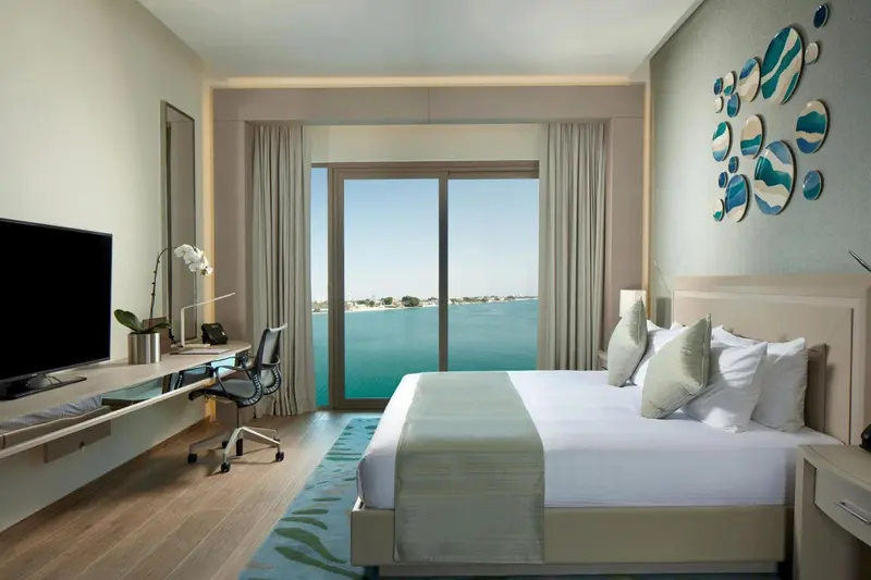 Une chambre lumineuse avec un grand lit et une vue sur la mer.