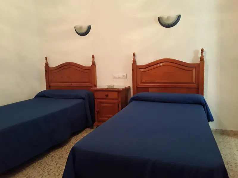 Deux lits simples dans une chambre aux murs clairs.