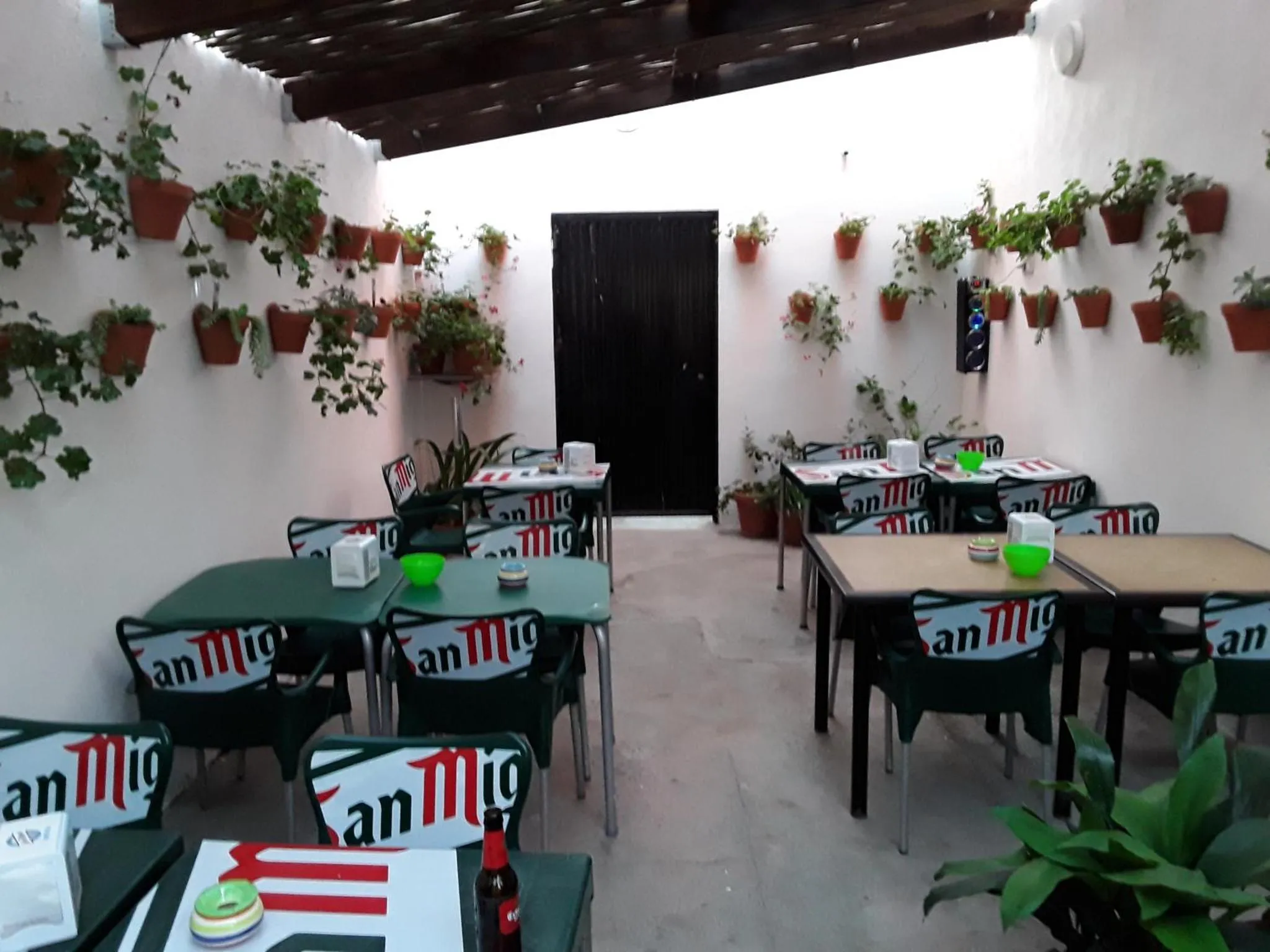 Une terrasse ombragée avec des tables et des chaises vertes.