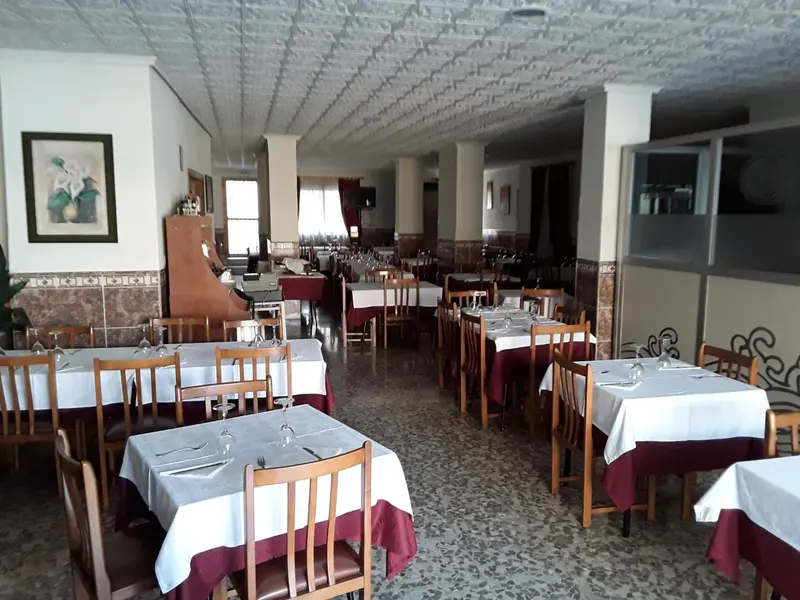 Une salle de restaurant lumineuse avec des tables dressées pour le service.