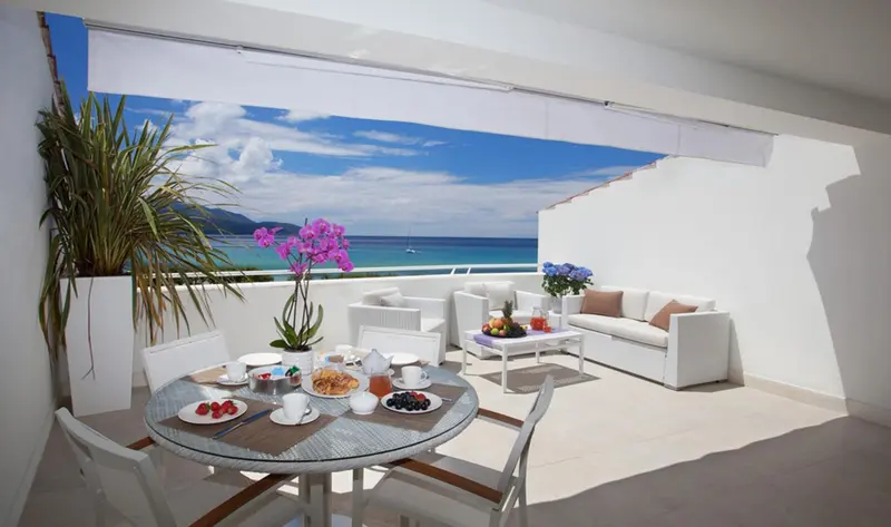 Une table est dressée sur une terrasse avec vue sur la mer.