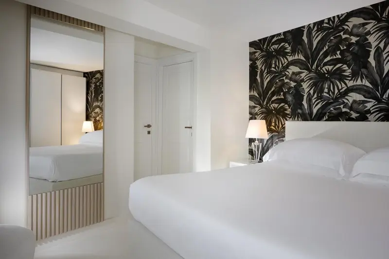 Une chambre lumineuse avec un grand lit et un mur décoré de motifs végétaux.