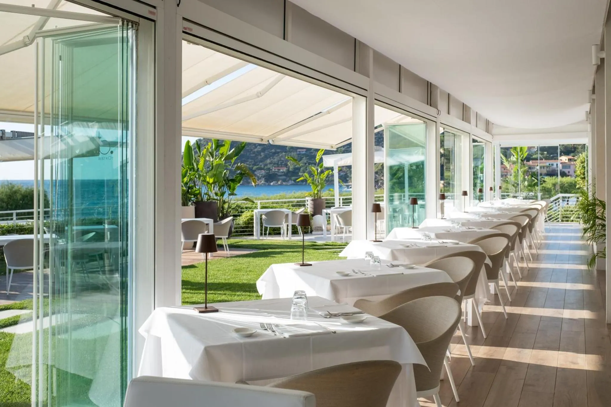 Une salle à manger lumineuse donne sur une pelouse verdoyante et la mer.