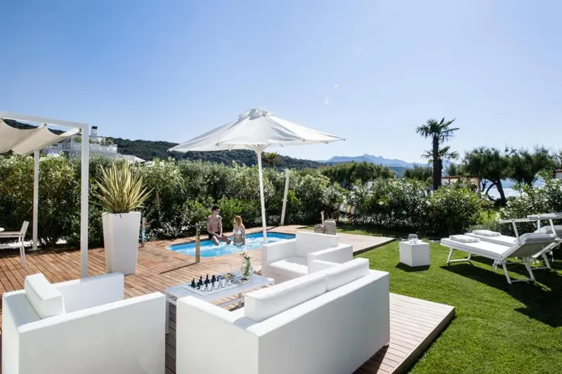 Espace extérieur aménagé avec salon blanc et petite piscine.