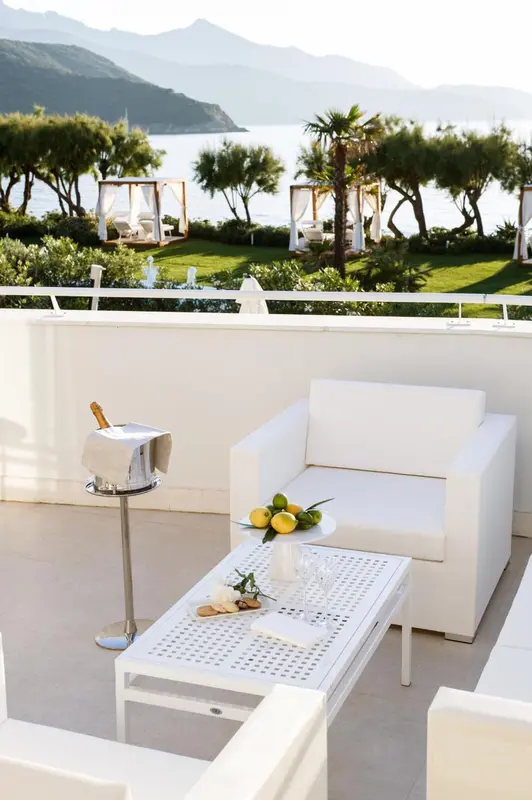 Mobilier blanc sur une terrasse ensoleillée avec vue sur la mer.
