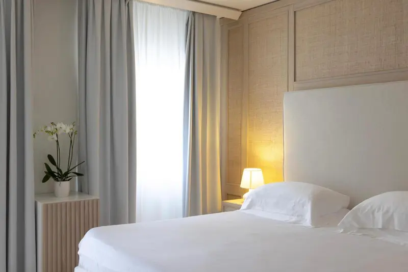 Une chambre lumineuse avec un grand lit et des rideaux clairs.
