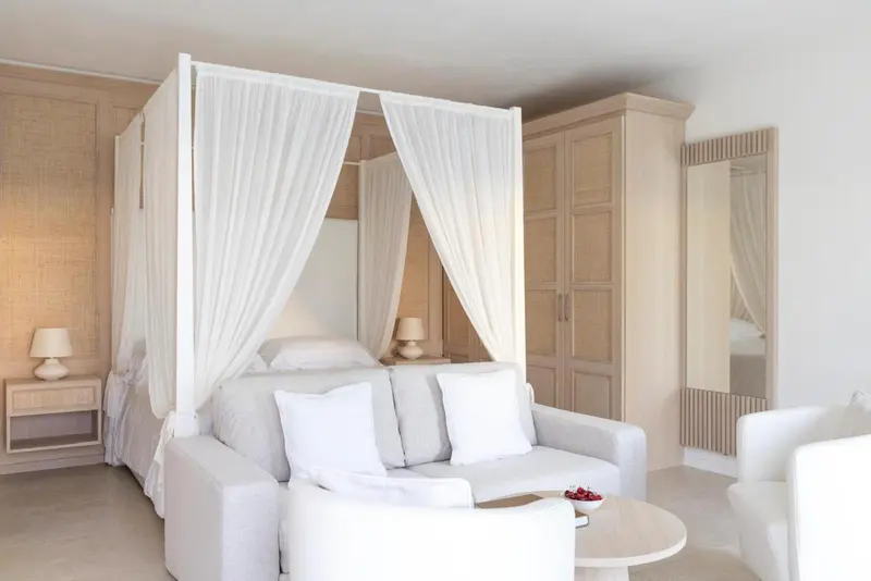 Une chambre lumineuse avec un lit à baldaquin et un coin salon.
