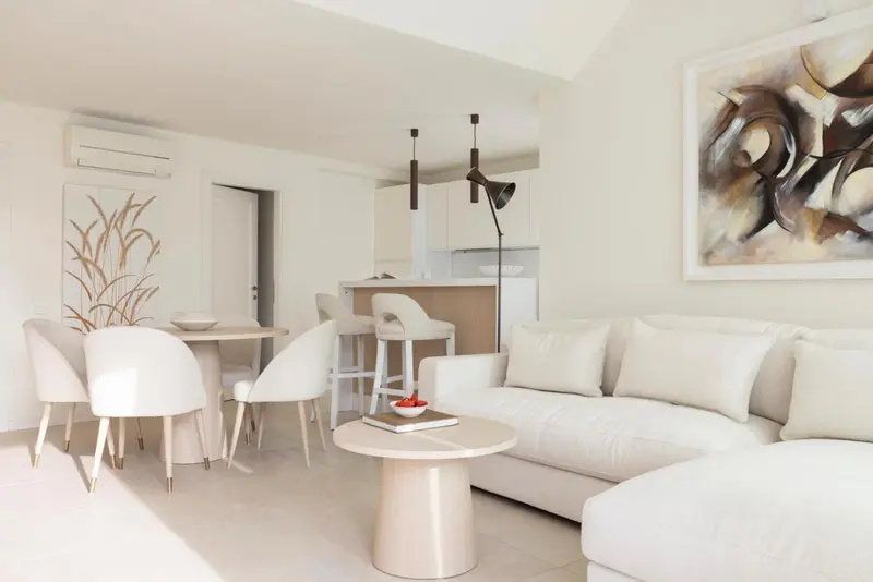 Un salon clair avec un canapé d'angle et une table basse devant un tableau.